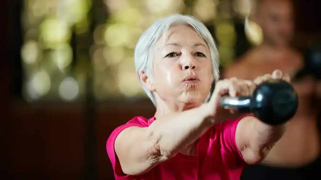 Older woman doing weight training Addlestone to help her strength and longevity 